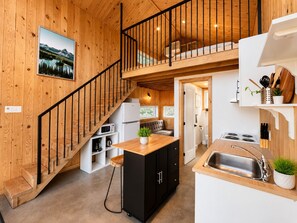 Ein Holzinnenraum mit Küche, Essbereich und Treppe.
