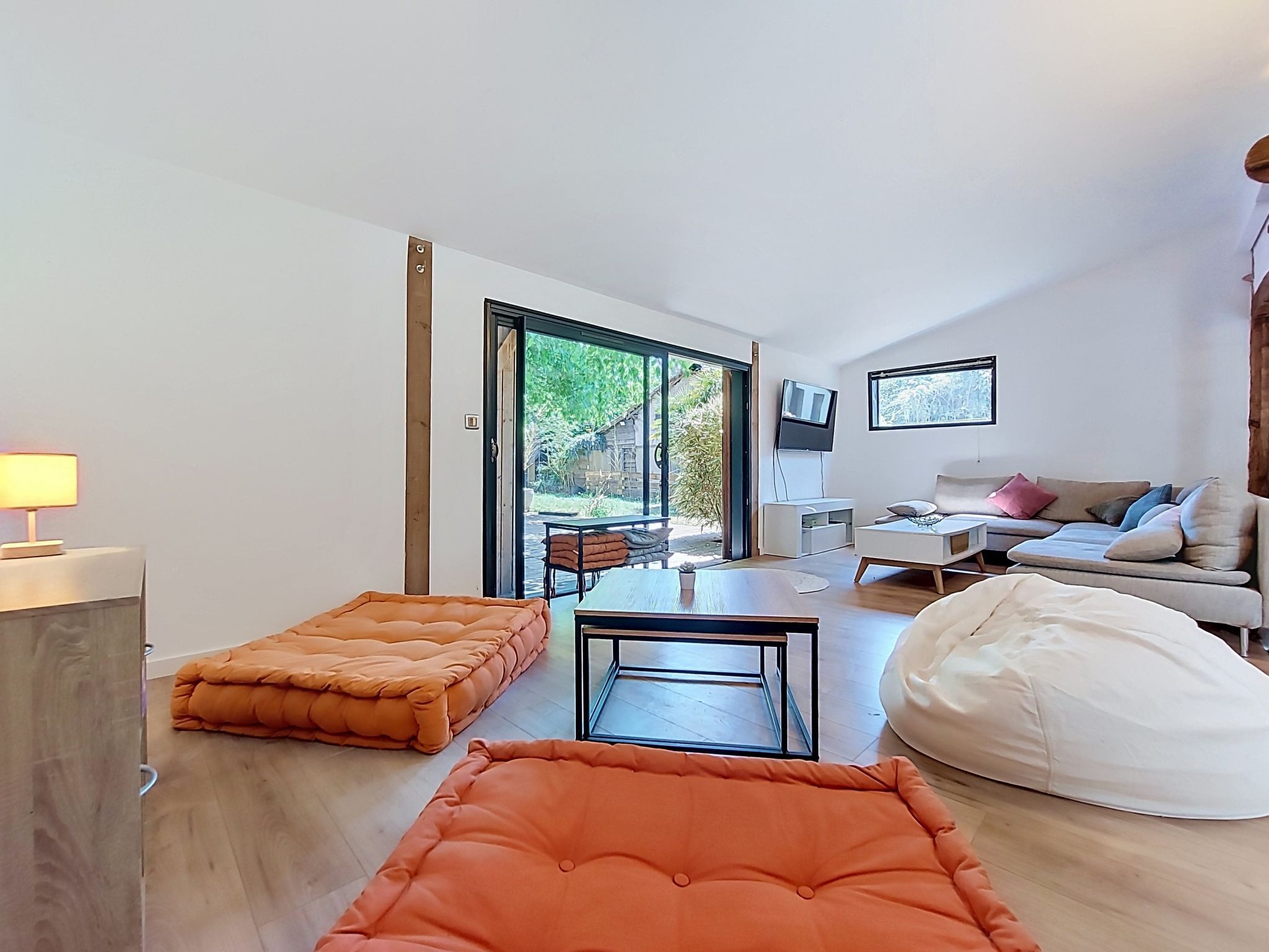 A modern living room with a sofa, ottoman, and a flat-screen TV.