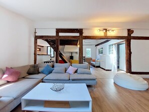 A living room with a sectional sofa, a coffee table, and a white bean bag. There is a staircase leading to another level. - La landaise by Interhome (Saint-Vincent-de-Tyrosse)