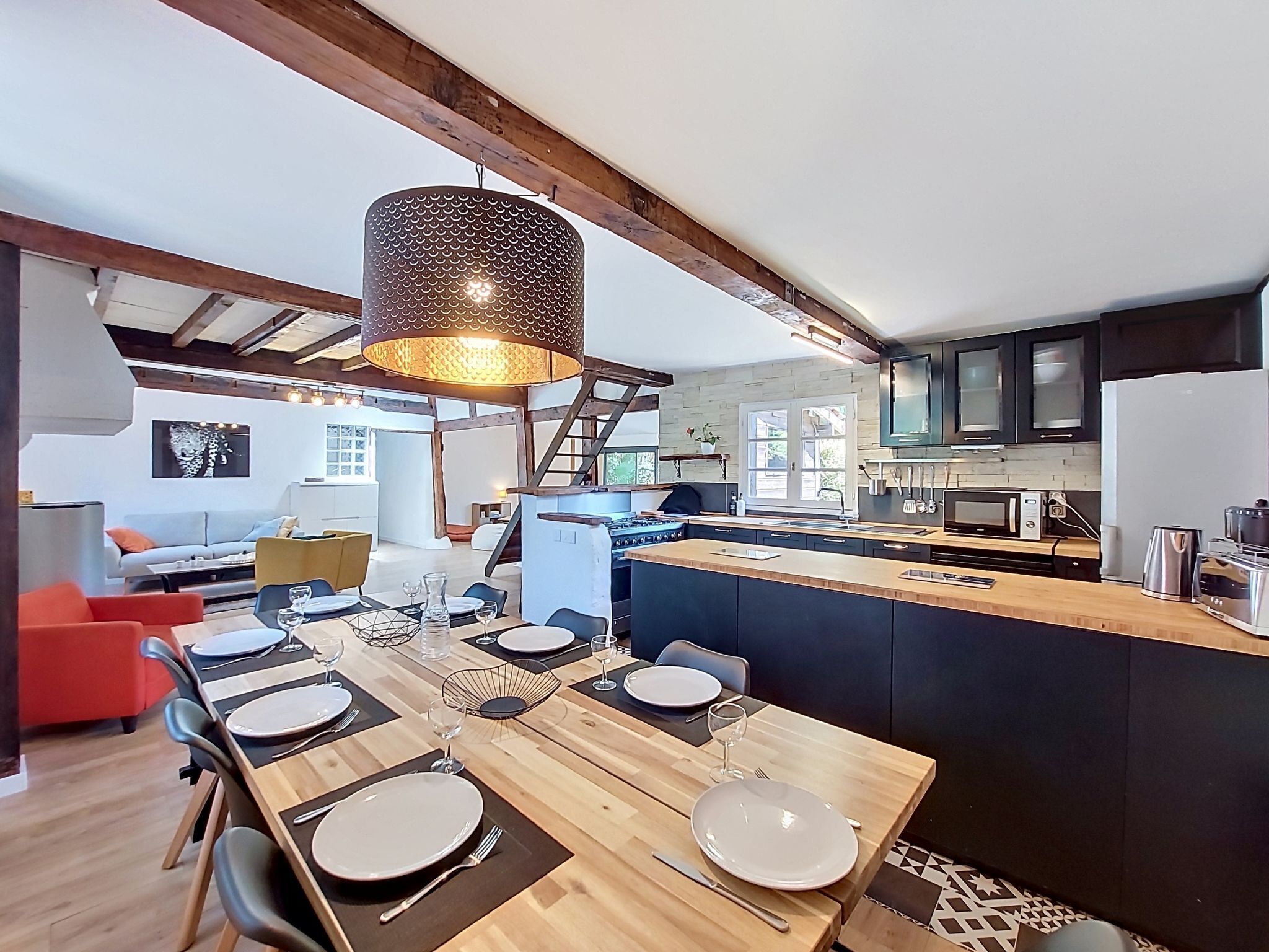 Een moderne keuken met een centraal eiland, houten vloeren en een eethoek met een tafel voor vier personen.