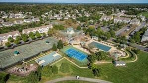 Ein Luftbild eines Wohngebiets mit Häusern, einem Tennisplatz und einem Schwimmbad.