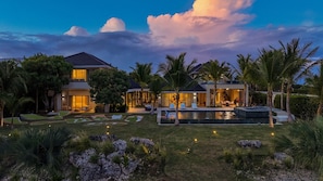Ein modernes Haus mit Pool, umgeben von tropischer Vegetation.
