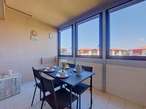 Ein Essbereich mit einem Tisch für zwei Personen, einem Heizkörper und einem Fenster mit Blick auf Gebäude.