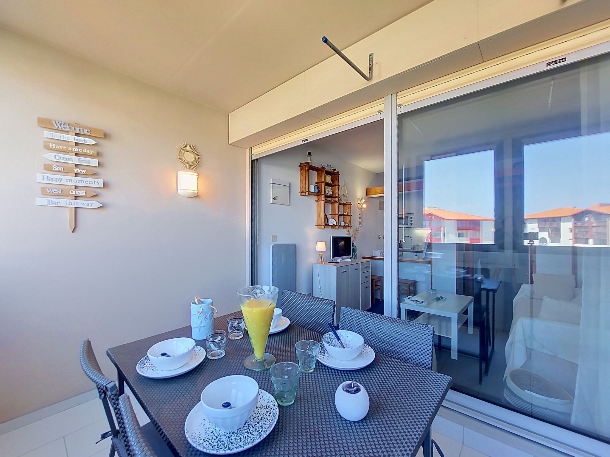 A dining area with a table set for two, a large window, and a wall-mounted sign with directional phrases.