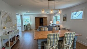 A dining area with a wooden table and plaid chairs, a map on the wall, and a view of the outdoors.