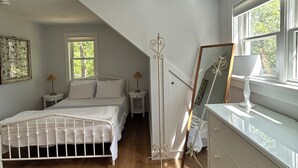 A bedroom with a bed, bedside tables, a dresser, a mirror, and a window.