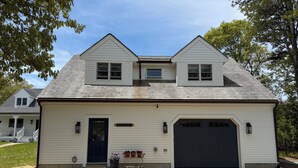 A two-story house with a dark front door, a garage, and a small porch with potted plants.