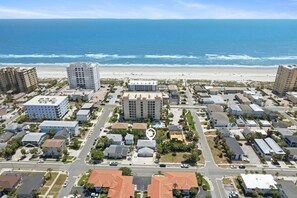 Un quartier résidentiel situé sur la côte, avec des propriétés donnant sur la plage, une rue principale et un hôtel doté d’une piscine.