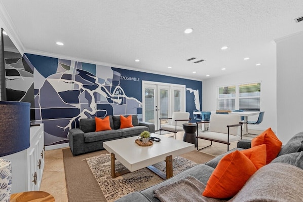 A modern living room with a sectional sofa, a coffee table, and a dining area with a table and chairs.