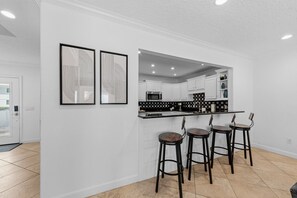 Une cuisine avec des armoires blanches, un comptoir noir et trois tabourets de bar.