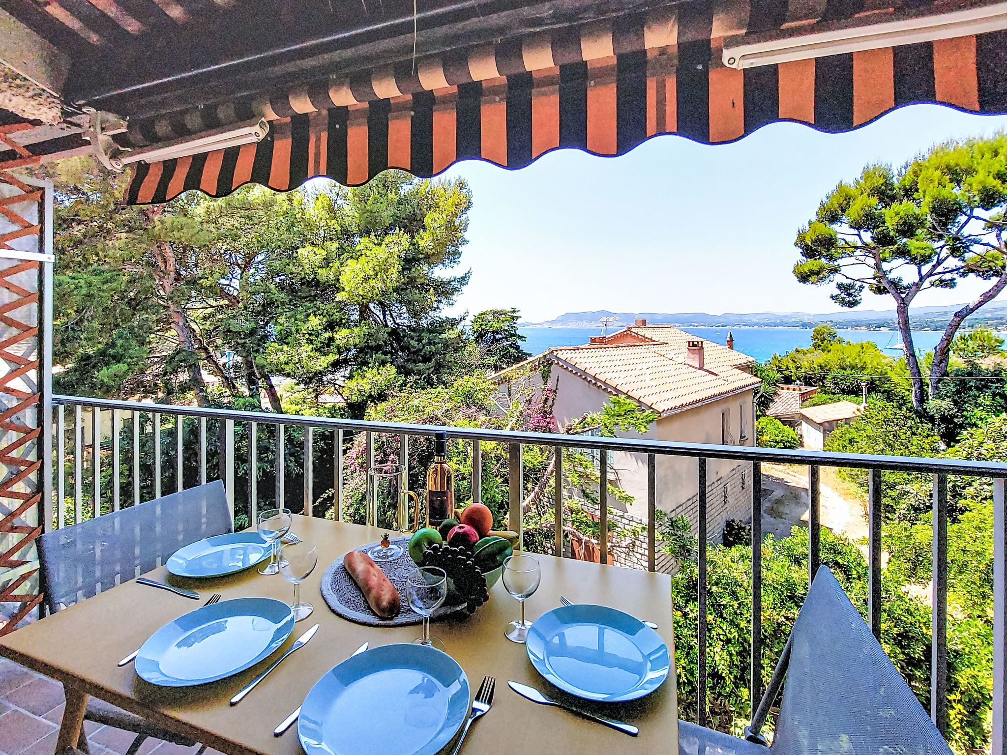 A balcony with a table set for four, overlooking a coastal landscape.