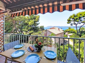 A balcony with a table set for four, overlooking a coastal landscape. - Les Aigues Marines by Interhome (Saint Cyr sur Mer La Madrague)
