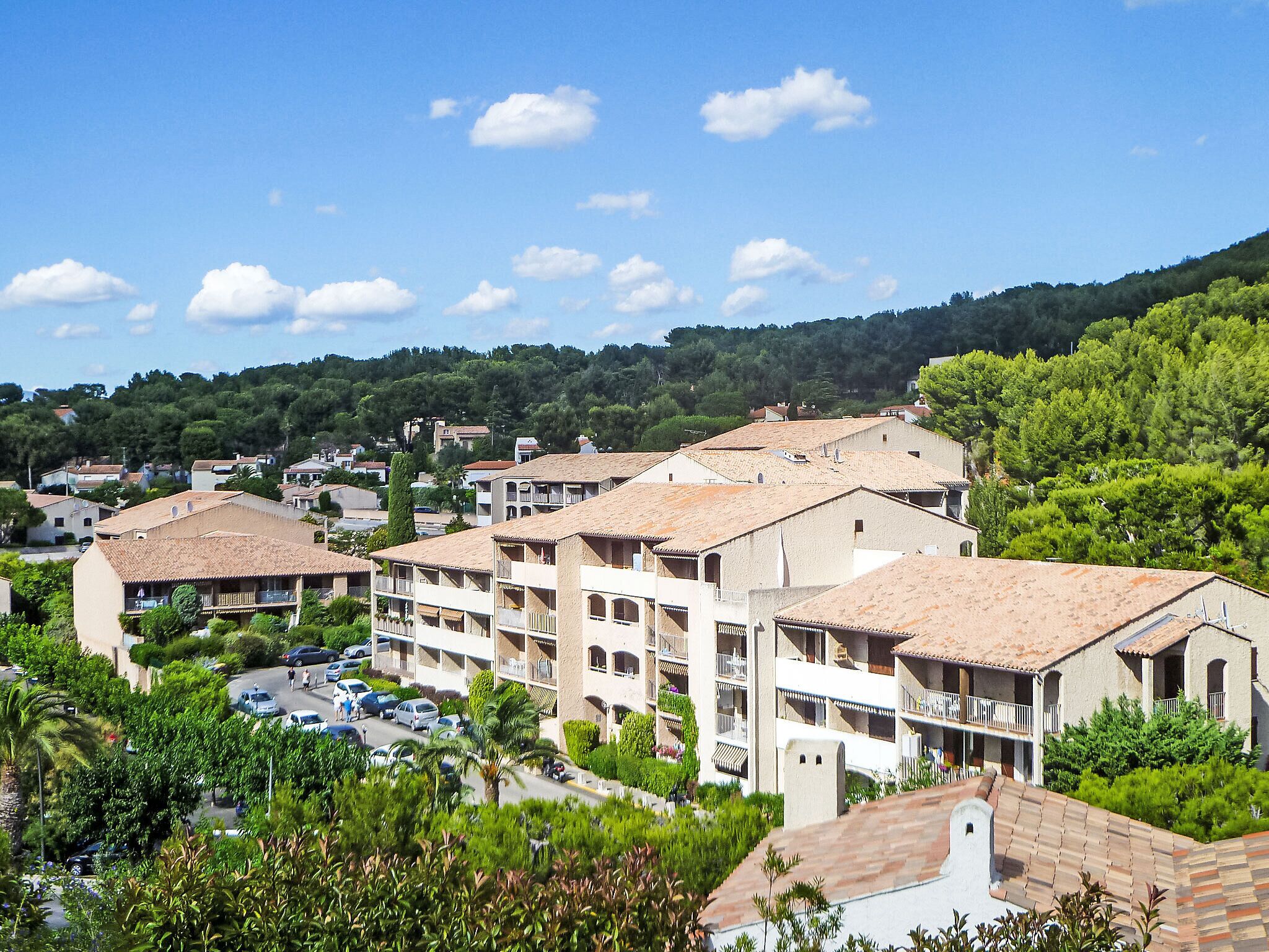 A residential area with multi-story buildings, a parking lot, and lush greenery.