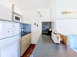 Eine kleine Küche mit einer Mikrowelle, einem Toaster und einem Spülbecken.