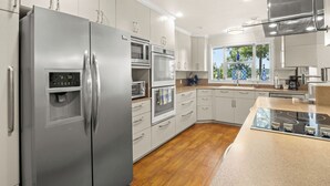 A modern kitchen with stainless steel appliances, white cabinetry, and a wooden floor. - Toledo Bend Lake House: Peaceful Retreat with Direct Waterfront Access (Hemphill)
