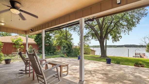 A covered patio with a ceiling fan, a wooden table, and two rocking chairs. - Toledo Bend Lake House: Peaceful Retreat with Direct Waterfront Access (Hemphill)