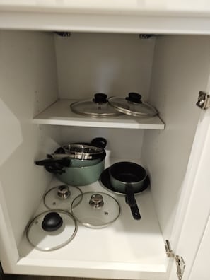 Een keuken met twee kookplaten, diverse pannen en een ingebouwde oven.