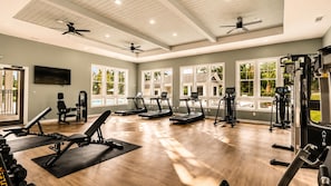 A gym with treadmills, weight machines, and a ceiling fan. - Modern Lakeview Oasis, King Bed • Gym • Pool (Jacksonville)