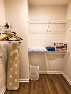 A small laundry room with a drying rack, ironing board, and storage shelves. - Modern Lakeview Oasis, King Bed • Gym • Pool (Jacksonville)