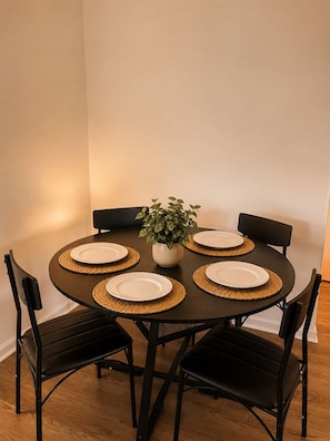 A round dining table with four chairs, a potted plant, and plates with placemats. - Modern Lakeview Oasis, King Bed • Gym • Pool (Jacksonville)