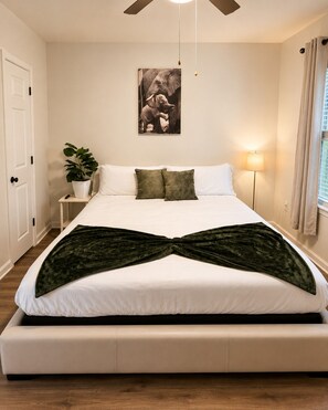 A bedroom with a bed, a potted plant, a wall-mounted picture, and a floor lamp. - Modern Lakeview Oasis, King Bed • Gym • Pool (Jacksonville)