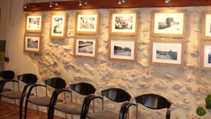 A room with stone walls, wooden beams, and framed photographs. There are chairs and a sofa. - Ideal for a group of 4 families, between two natural parks, the sea and Port Aventura. (Camarles)