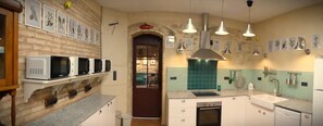 Een keuken met een bakstenen muur, een ingebouwde magnetronplank, een fornuis en een spoelbak.