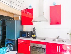 Eine kompakte Küche mit Waschmaschine, Kaffeemaschine und Mikrowelle.