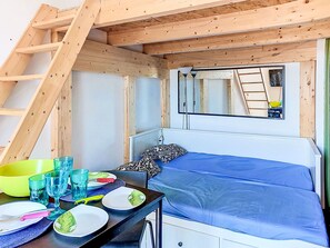 Ein kleiner, kompakter Raum mit einem Etagenbett, einem Tisch mit Geschirr und Gläsern sowie einer Treppe.