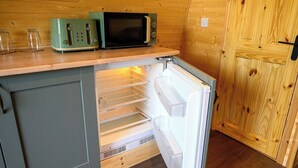 Una cocina compacta con microondas integrado, tostadora y refrigerador.