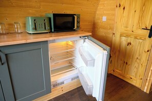 A compact kitchen with a built-in microwave, a toaster, and a refrigerator.