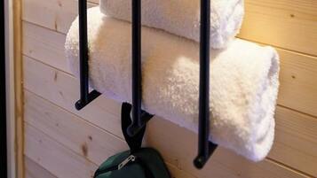 A wooden wall with a metal towel rack holding two folded towels and a potted plant.