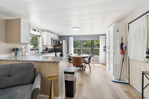 Una cocina moderna con comedor, un sofá y un cubo de basura.