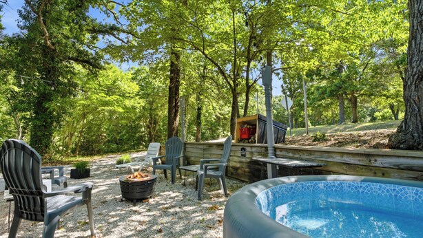 Un espace piscine doté d’un jacuzzi, entouré d’arbres et agrémenté de mobilier d’extérieur.