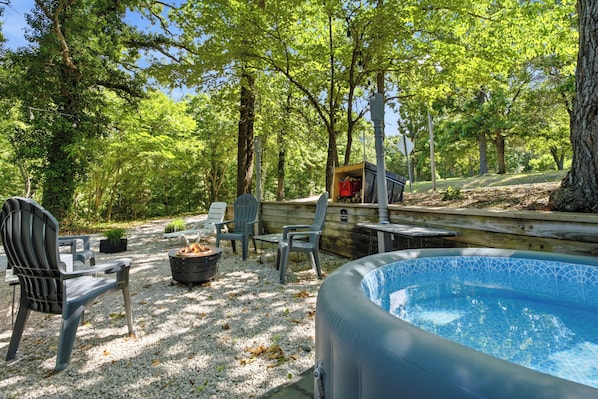 Zona de piscina con hidromasaje, rodeada de árboles y mobiliario exterior.