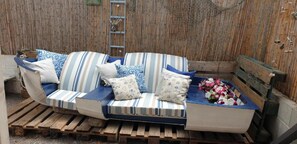 En randig soffa med kuddar, en träbänk och en blomsteruppsättning.