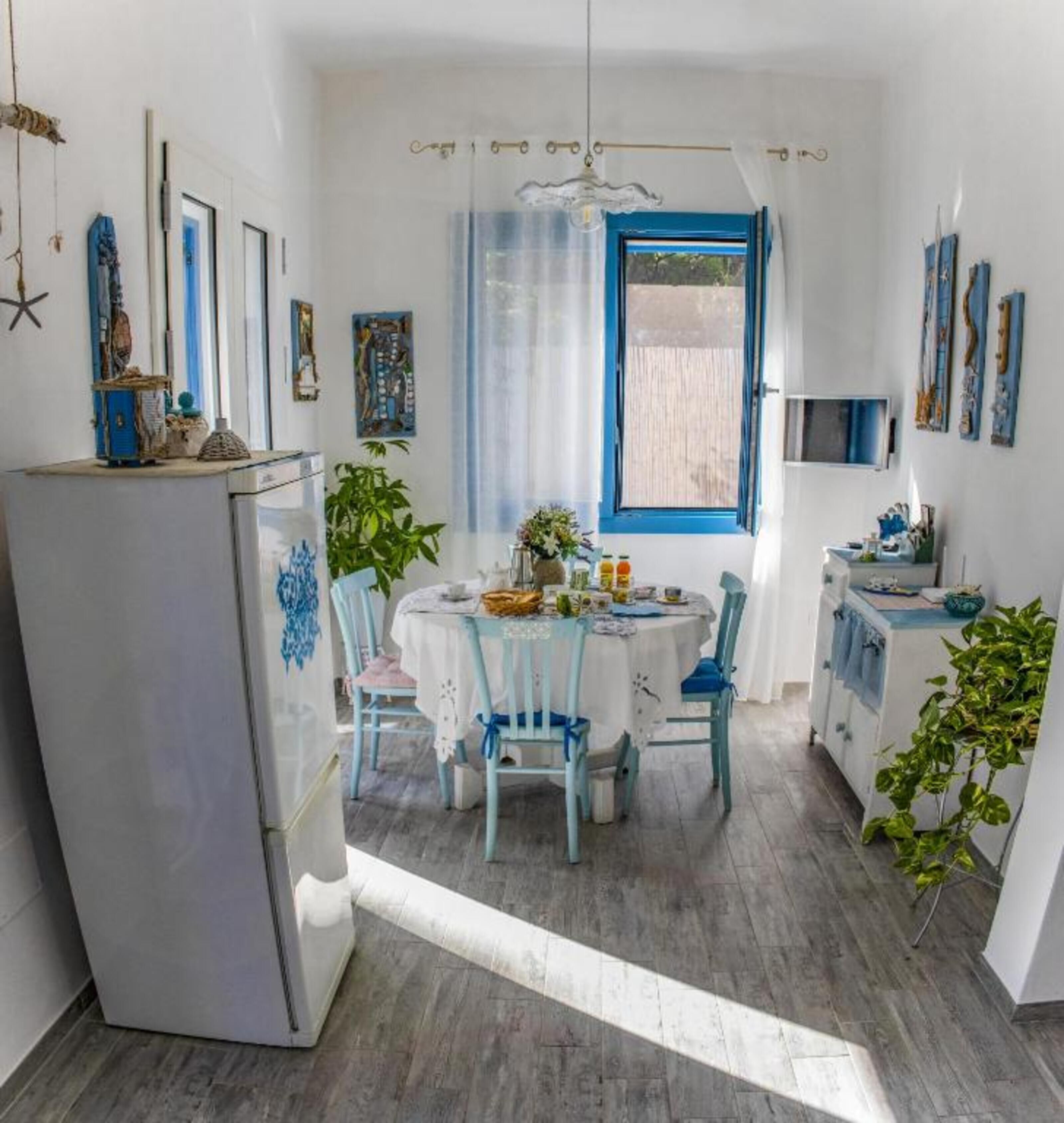 Una cocina compacta con comedor, un refrigerador y una ventana con cortinas.