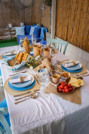 Une table à manger dressée avec des assiettes, des couverts, des verres et un panier de pain.