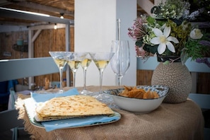 Une table avec un pain plat plié, un bol de collations et trois verres de vin blanc.