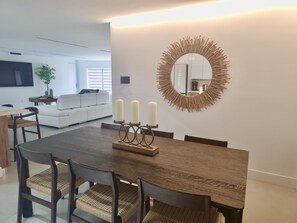 A dining area with a wooden table, woven chairs, and a wall-mounted mirror with a fringe design. - Coral Springs Oasis Retreat (Coral Springs)