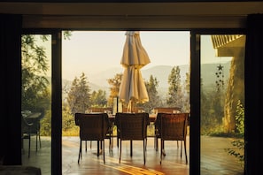 Ein Essbereich im Freien mit Korbstühlen und einem Tisch, mit Blick auf eine Berglandschaft.