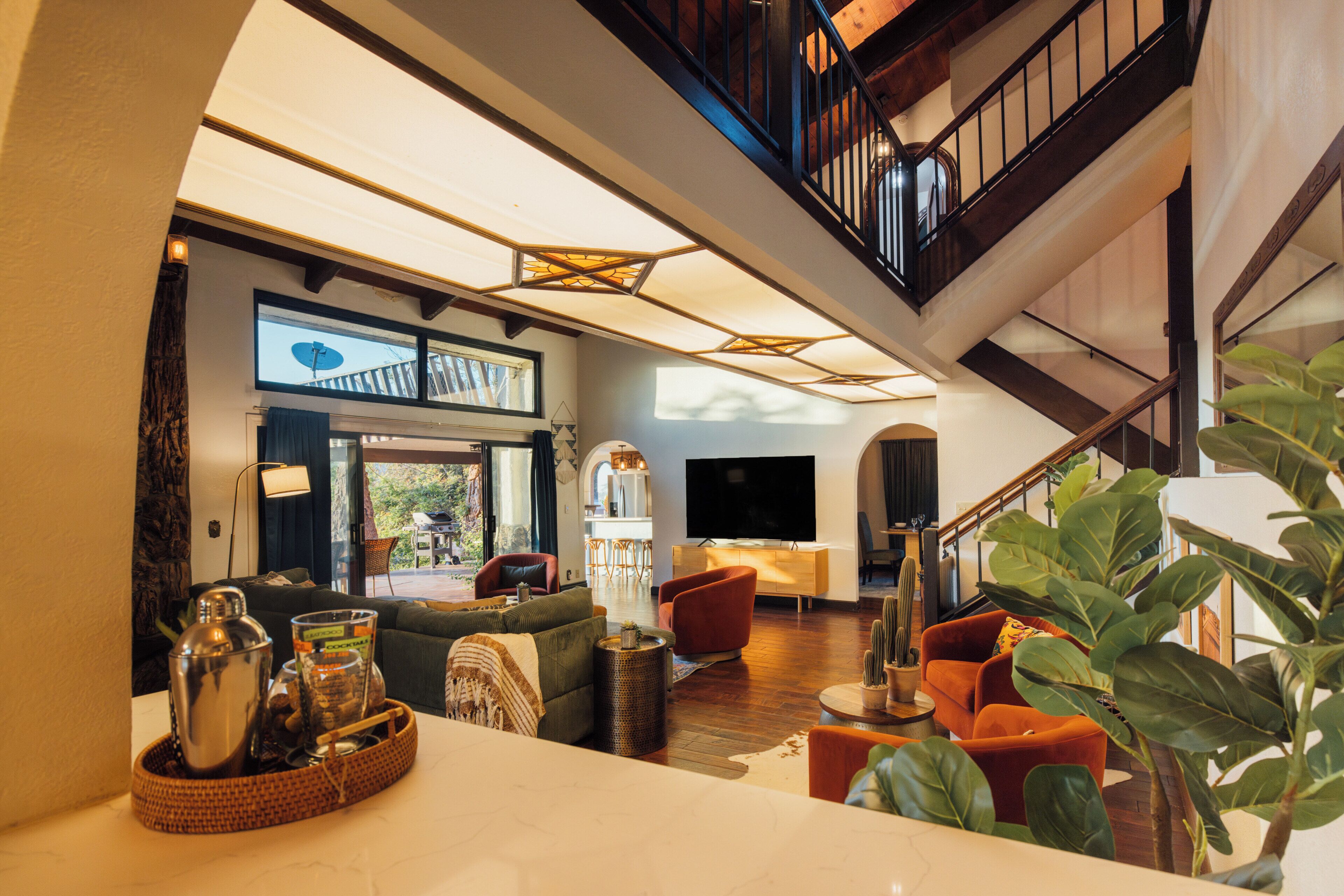 Uma sala de estar espaçosa com design moderno, uma escada e uma televisão de tela plana grande.