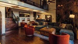 Ampla sala de estar com escada, piso de madeira e parede de destaque em pedra.