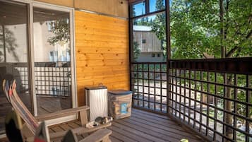 A wooden deck with a glass door, a trash bin, and a small table with items on it.