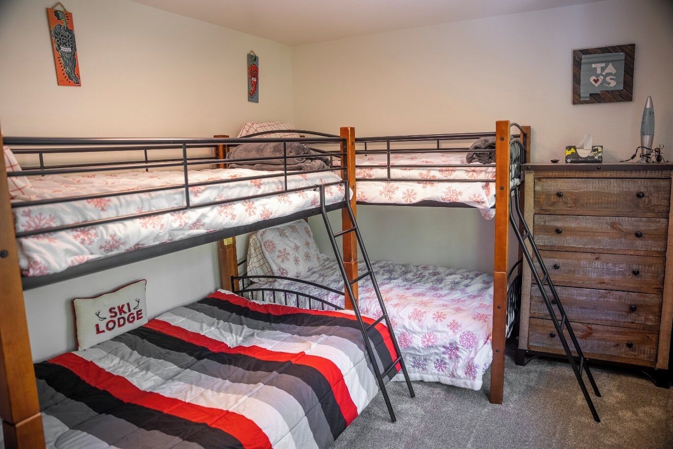 A bunk bed room with a wooden dresser and a ladder.