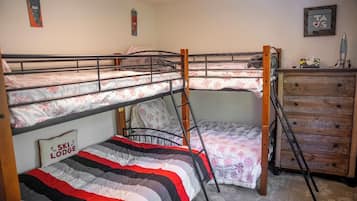 A bunk bed room with a wooden dresser and a ladder.