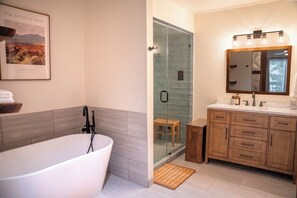 Une salle de bain moderne avec une baignoire sur pieds, une douche à parois de verre et des meubles en bois.