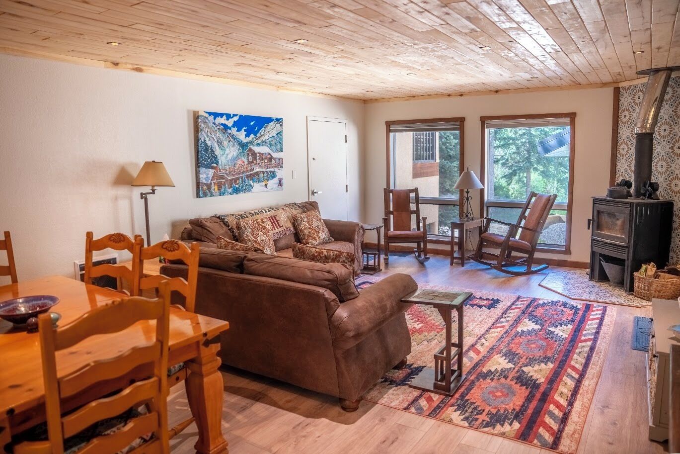 A cozy living room with a brown sofa, wooden chairs, a dining table, and a fireplace.