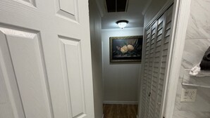 A hallway with white doors, a framed picture on the wall, and a tiled floor. - Tranquil 3-bedroom house with AC in charming Eastman (Eastman)