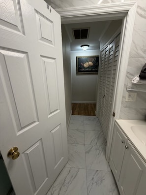 A hallway with white doors, a framed picture on the wall, and a tiled floor.